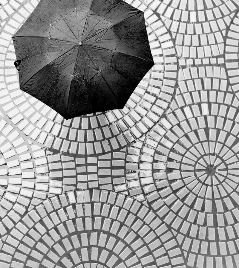 Parapluie noir vu du dessus sur des pavés en éventail
